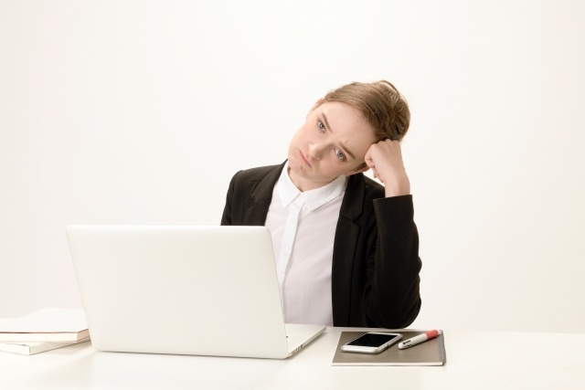パソコン前で頭に手をついて悩む外人女性